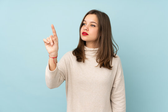 Teenager Girl Isolated On Blue Background Touching On Transparent Screen