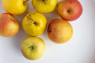 red and yellow organic apples from a rural garden on a white glossy plate string on a table with pink cover 