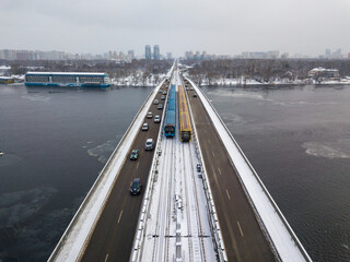Two metro trains on a snow-covered metro bridge in Kiev. Cloudy winter morning. Aerial drone view.