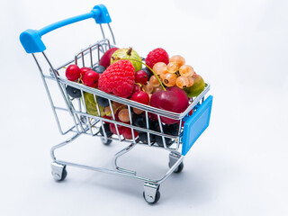 Mini grocery cart filled with fresh vitamin berries isolated on white background