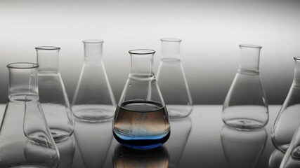 The blue liquid spills over water in laboratory flask. - Powered by Adobe