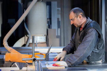 A furniture manufacturing worker at a cutting machine makes furniture parts. Furniture manufacturing.