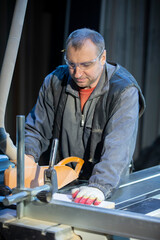 A furniture manufacturing worker at a cutting machine makes furniture parts. Furniture manufacturing.