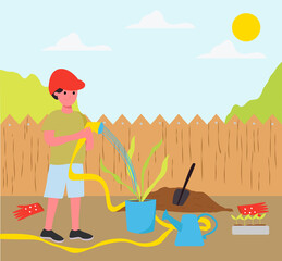Fototapeta premium A little boy waters a plant in the garden with a watering hose, a boy in the summer in the village