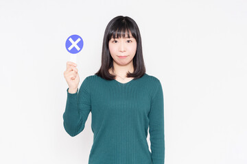 白背景のに立ってNGのプラカードを持っている女性