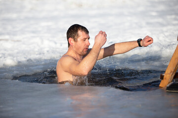 A man plunges into an ice-hole during the winter festival of the baptism of Jesus. A man swims in the ice-hole in winter. Walrus people.