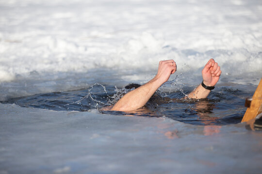 A man plunges into an ice-hole during the winter festival of the baptism of Jesus. A man swims in the ice-hole in winter. Walrus people.