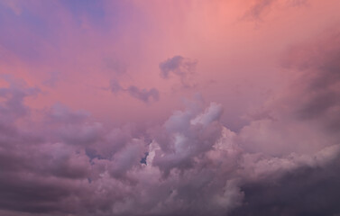 Clouds in the blue sky at sunset or dawn backlit by the sun. Place for text and design. Heaven and clouds with copy space. Looking up in the sky. Wallpaper picture. View into infinity