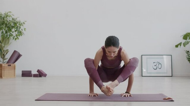 Wide shot of Caucasian female yogi wearing sportswear practicing yoga in yoga studio