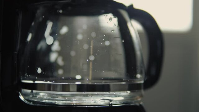 Drip coffee maker brews freshly brewed coffee. Close up of fresh hot coffee dripping into pot