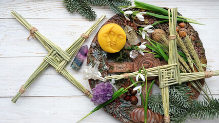 Winter altar for Imbolc sabbath. spring pagan holiday ritual. Brigid's cross, candle, wheel of the year, snowdrops, sun and moon symbol - items of Imbolc holiday, spring equinox. flat lay