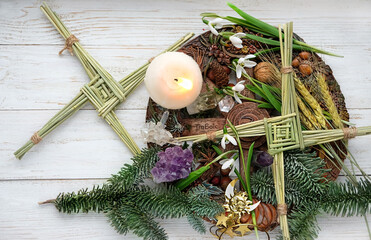 Winter altar for Imbolc sabbath. spring pagan holiday ritual. Brigid's cross, candle, wheel of the...