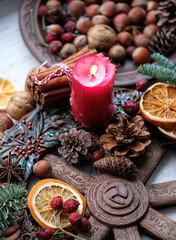 Winter altar for Yule sabbath. pagan holiday. Red candle, wheel of the year, cinnamon, nuts, cones,...