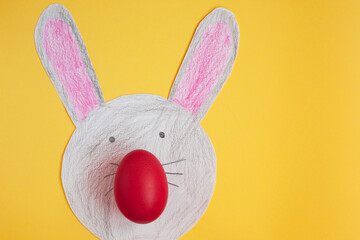 cute Easter hare with egg nose and long ears on a yellow background