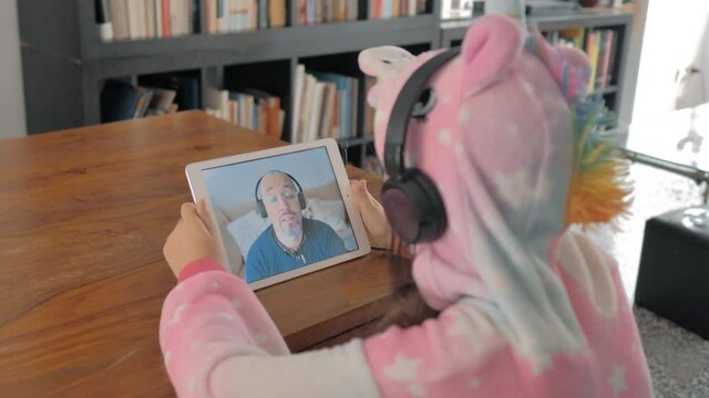 Videoconferencia de ni&ntilde;a con su padre con una Tablet y 
 con  auriculares 