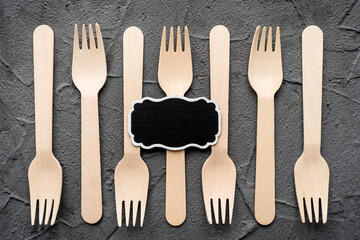 Wooden knife and fork on the black background. Eco friendly zero-waste concept. Top view with space for text. Copy space