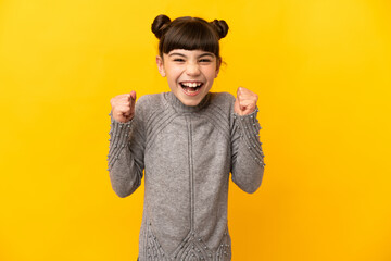 Little caucasian girl isolated on yellow background celebrating a victory in winner position