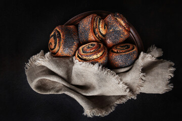 Butter rolls with poppy seeds in a ceramic plate with a cotton napkin. Top view.