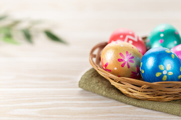 Obraz na płótnie Canvas Five easter eggs trendy colored deep blue, green, orange, magenta and golden decorated in basket on white background. Copy space for text.