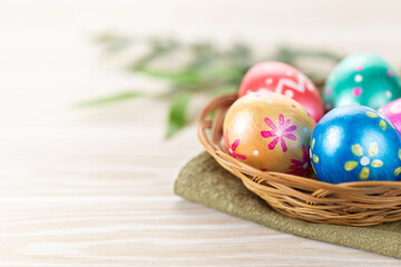 Fototapeta na wymiar Five easter eggs trendy colored deep blue, green, orange, magenta and golden decorated in basket on white background. Copy space for text.