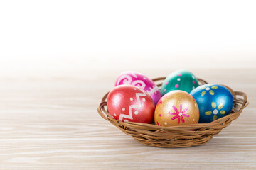 Fototapeta na wymiar Five easter eggs trendy colored deep blue, green, orange, magenta and golden decorated in basket on white background. Copy space for text.