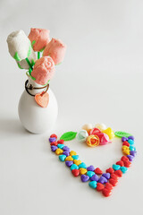 Creative composition of colorful candies and marshmallows on a stick in the shape of a rose on a light background. copy space