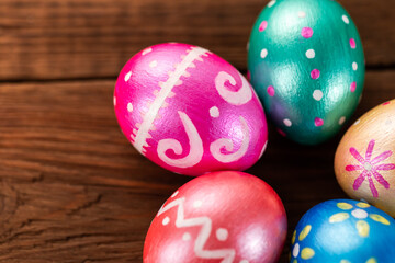 Fototapeta na wymiar Five easter eggs trendy colored classic blue, green, orange, magenta and golden decorated on old wooden table. Copy Space.