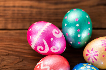 Fototapeta na wymiar Five easter eggs trendy colored classic blue, green, orange, magenta and golden decorated on old wooden table. Copy Space.
