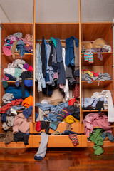Huge closet filled with used clothes, sloppily shoved and hanging from shelves and hangers....
