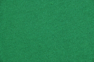 Background, texture. Knitted fabric with a small pattern in green. Material for designers.