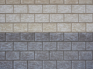 Wall cladding in rough gray and beige tiles imitating masonry. Not seamless texture