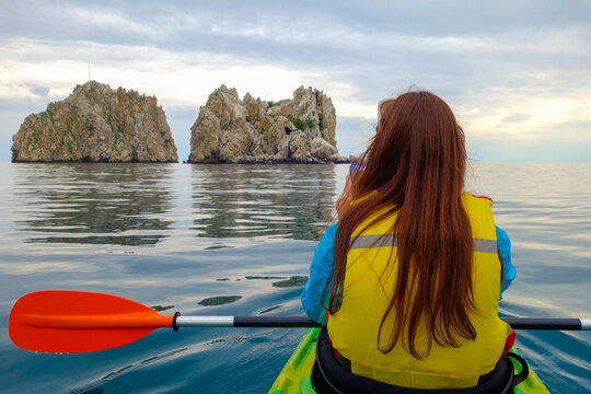 A girl with long hair in a kayak takes pictures of the beautiful islands