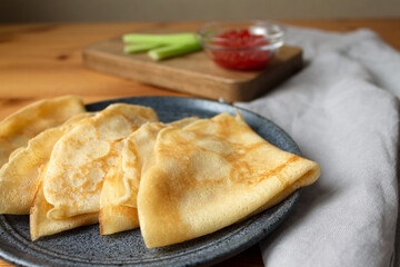 Ready-made nutritious breakfast dish Russian pancakes with milk with red caviar and celery.