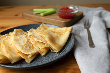 Ready-made nutritious breakfast dish Russian pancakes with milk with red caviar and celery.