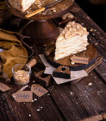 homemade tasty layered russian cake napoleon with white cream on rustic wooden boards and cake stand