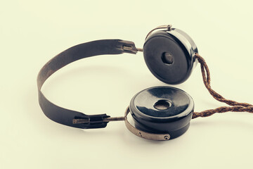 Old headphones. Close-up yellow toning vintage radio headphones on a light background. The concept...
