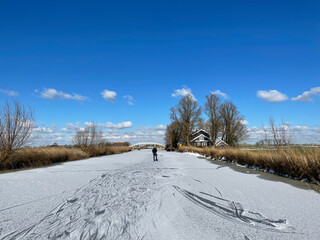 Obraz premium Man ice skating on a frozen canal in Friesland