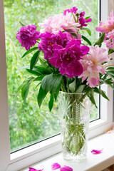 Vertical photo of peony flowers in vase on windowsill