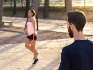 Fitness couple stretching outdoors in park. Young man and woman exercising together in morning.