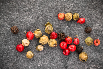 Peppercorns over black stone background. Top view.