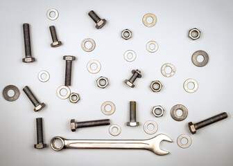Texture with bolts, nuts, washers and wrench on a gray background