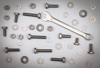 Bolts, nuts, washers and wrench on a gray background