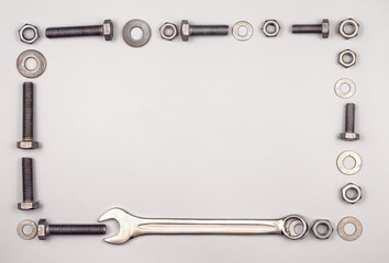 Frame with bolts, nuts, washers and wrench on a gray background