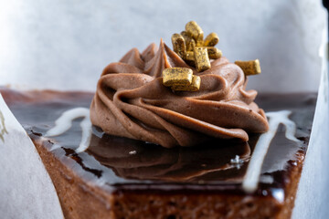 Piece of chocolate cake with cream and gold bars on it