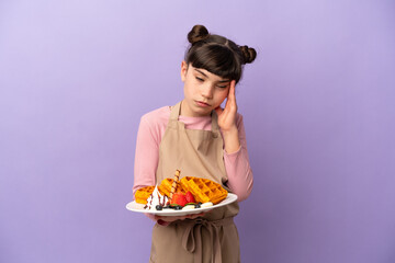 Little caucasian girl holding waffles isolated on purple background with headache