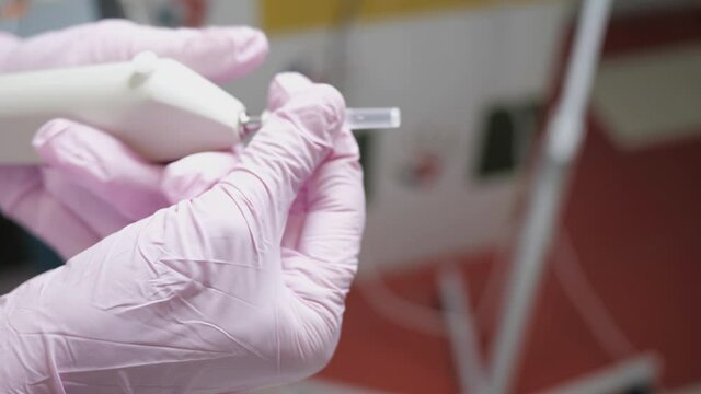 female hand of cosmetologist doctor in close-up places needle on device for gas injections of carboxytherapy