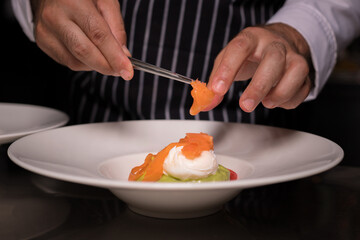 Chef cook preparing eggs in his kitchen. Eggs Benedict on toasted muffins with ham and sauce. Breakfast Buffet Concept, Breakfast Time. Various brunch on the table. 