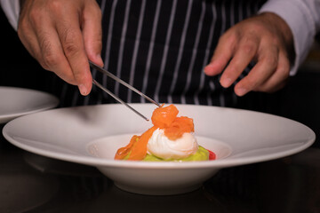 Chef cook preparing eggs in his kitchen. Eggs Benedict on toasted muffins with ham and sauce. Breakfast Buffet Concept, Breakfast Time. Various brunch on the table. 