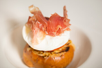 Chef cook preparing eggs in his kitchen. Eggs Benedict on toasted muffins with ham and sauce. Breakfast Buffet Concept, Breakfast Time. Various brunch on the table. 