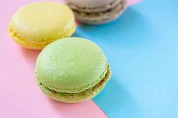 Close up view of macarons french dessert made of almond flour and fillings on two colored background. Green, yellow and brown cookies